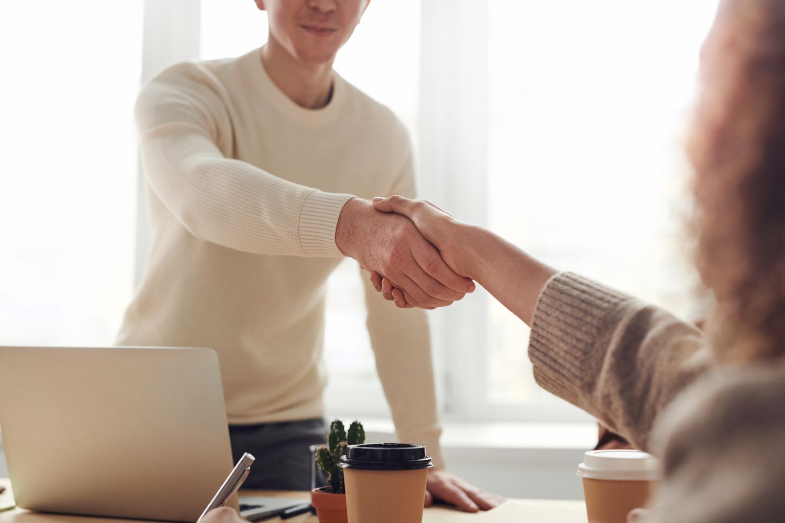 A friendly handshake across a desk at the start of a meeting