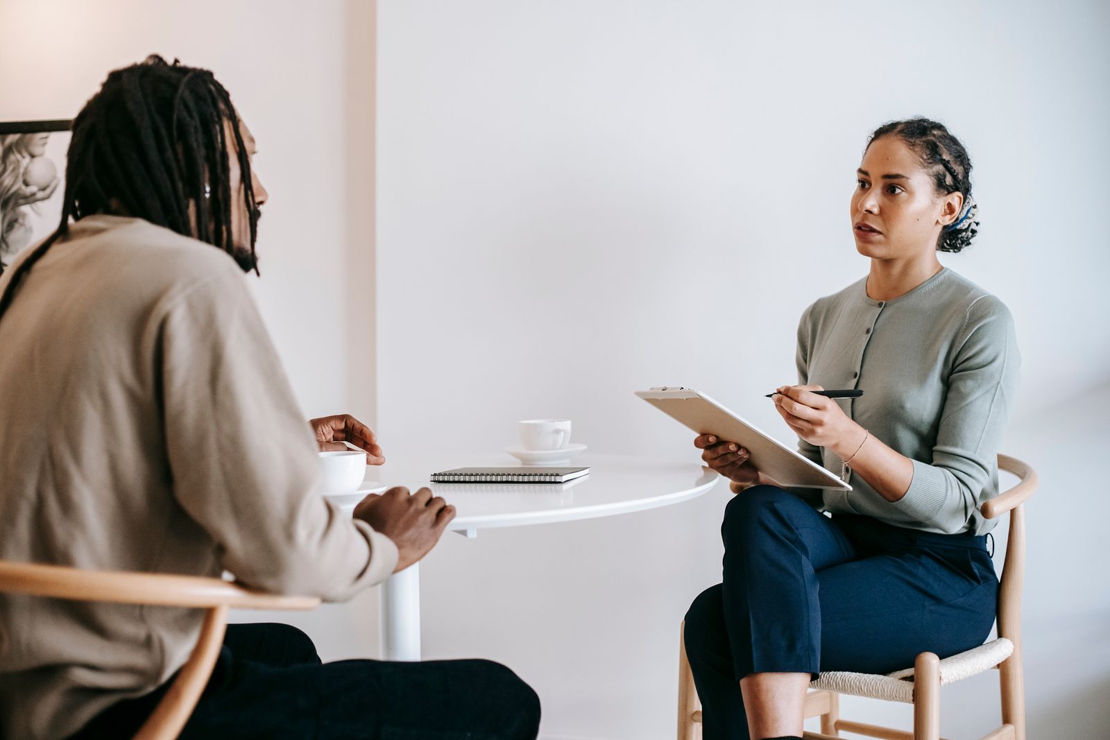 An advisor with a clipboard listening to a client across a table